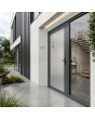 Puerta de entrada de aluminio color antracita con letrero de «Milk» y dirección transparente